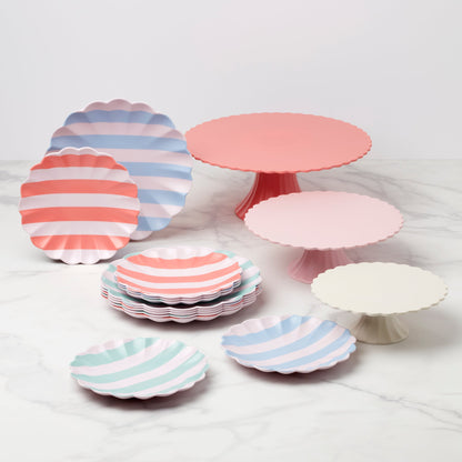 Set of colorful striped paper plates and cake stands on a white background